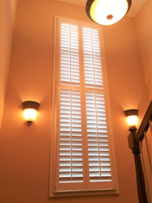 White plantation shutters in well-lit stairwell.